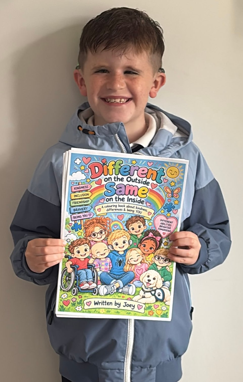Joey holding his finished colouring book, Different on the Outside, Same on the Inside
